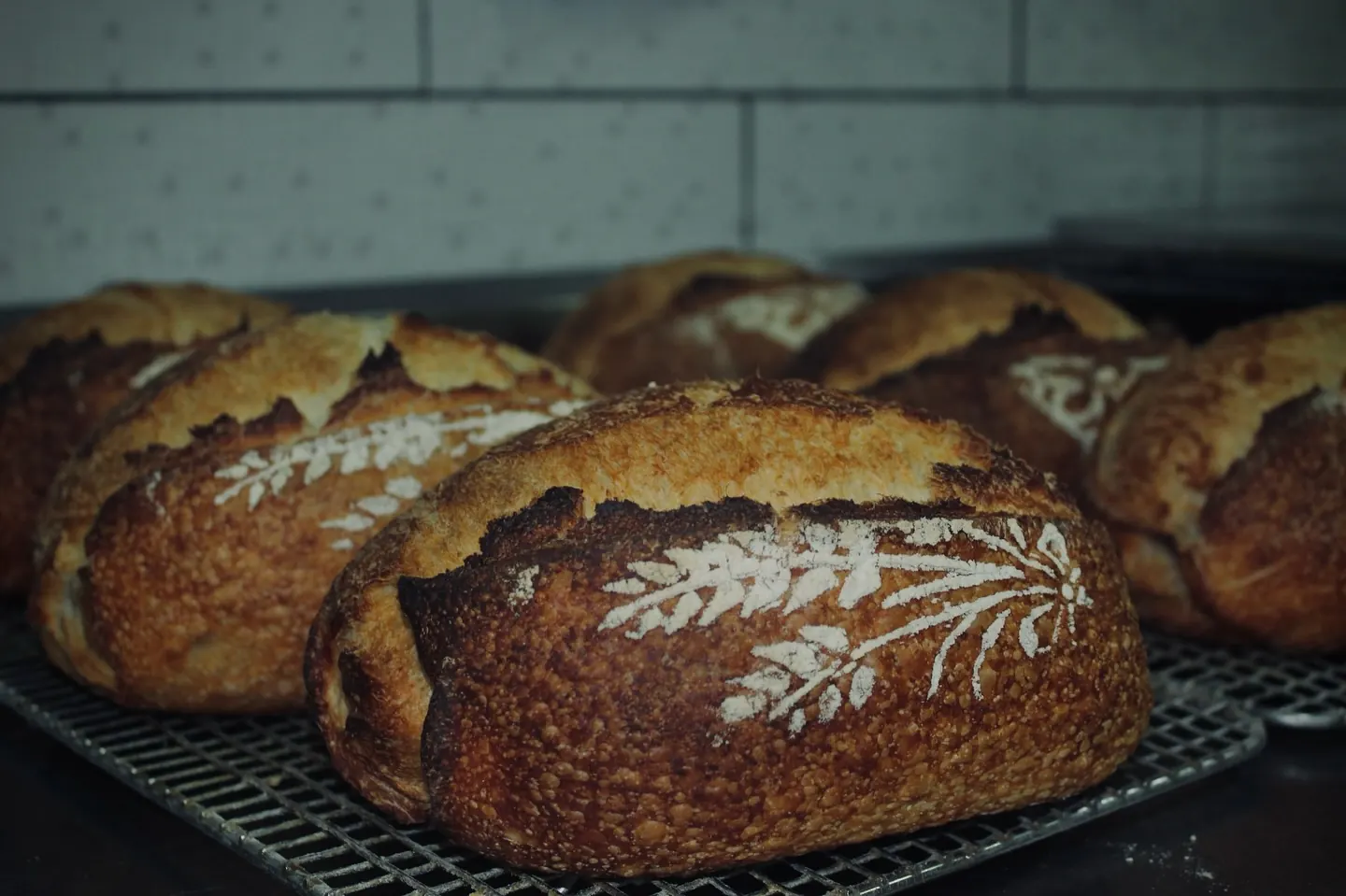 Hogazas de masa madre de Artesanypan recién horneadas, con una espiga de trigo dibujada en harina