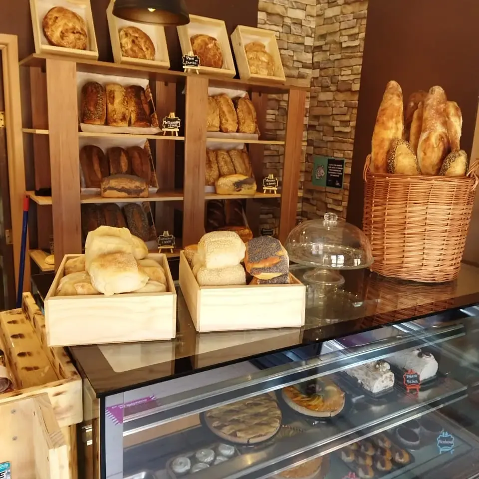 Interior del local de Artesanypan: repisas con panes y vitrina de pasteles